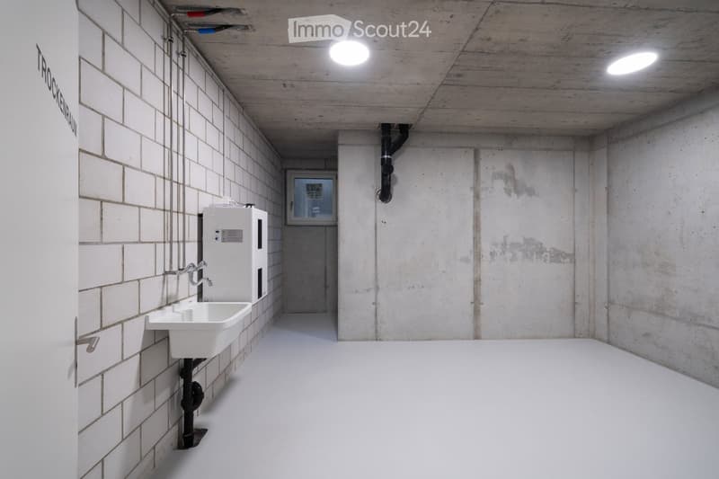 small room, concrete wall, white sink, white floor, pipe on wall