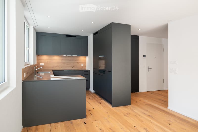 Modern kitchen with a wooden countertop, built-in oven, built-in dishwasher, under cabinet lighting, sleek cabinets, and an island sink with faucet