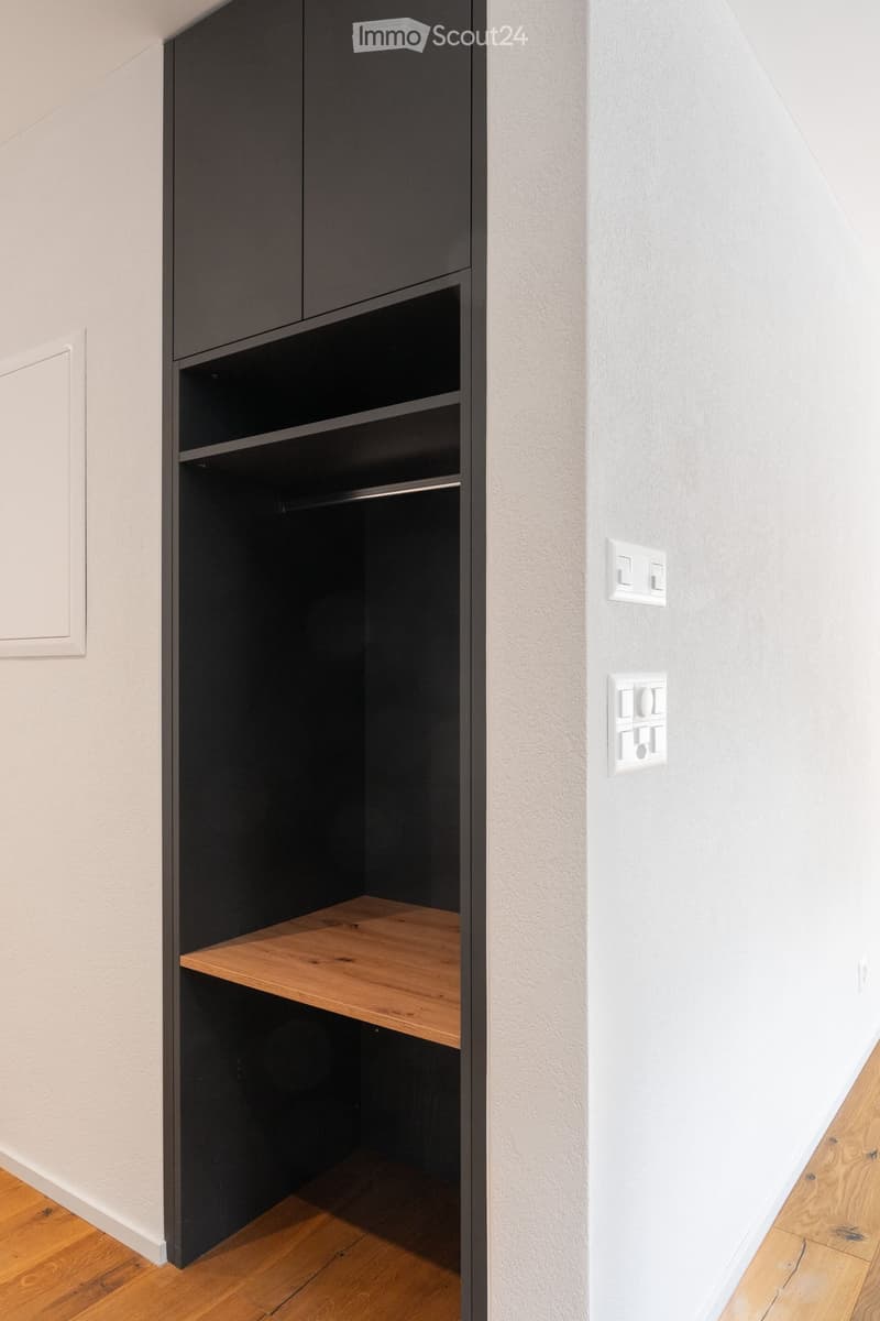 wooden shelf, white wall, black built-in closet, power outlets