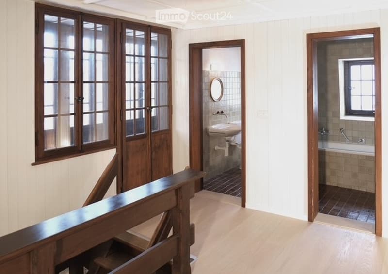 white walls, wooden floor, two windows, wooden handrail, sinks, mirror, bathtub