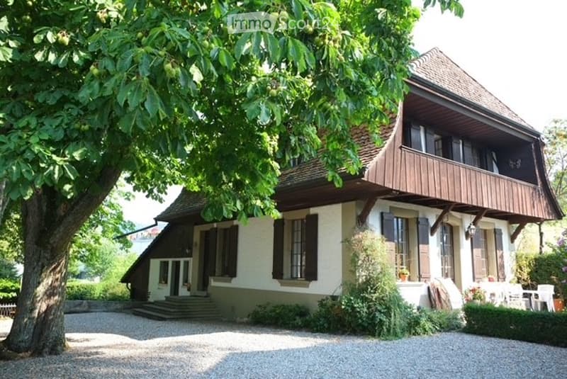 detached house, large tree, gravel driveway, balcony, wooden beams, white walls