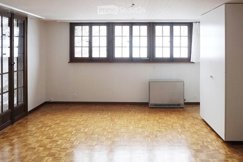 Empty room, hardwood floor, white walls, three windows, door, power outlet, and a white appliance