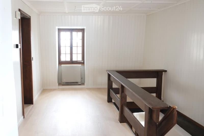 Raised ground floor, open interior, wooden railings, white ceiling, wooden door, window, heating system