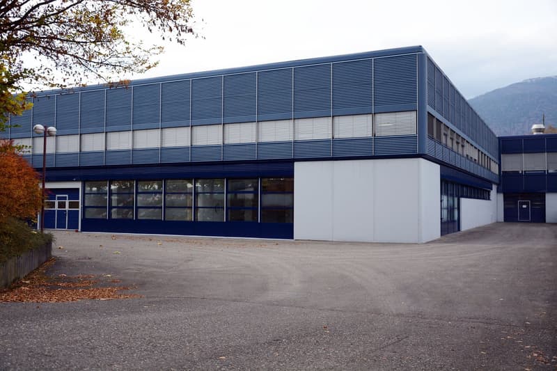 modern design, blue panels, white walls, multiple large windows, parking lot