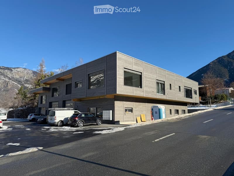 2 story building, grey exterior, multiple windows, cars parked outside