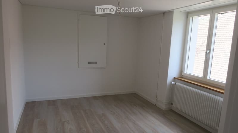 white walls, wooden floor, white radiator, window with wooden sill