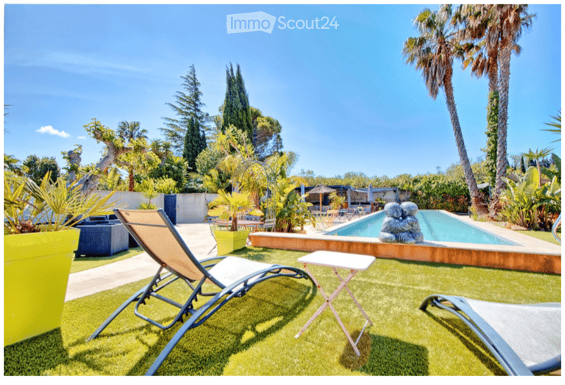 well-maintained garden with artificial grass, swimming pool, lounge chairs, and decorative plants