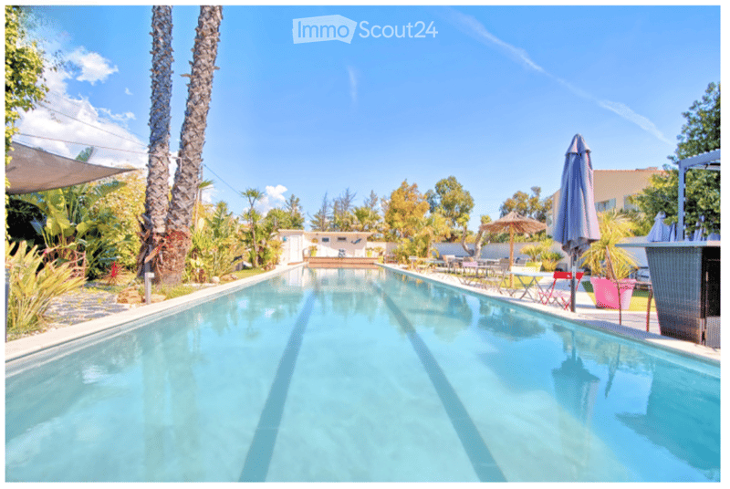Outdoor swimming pool surrounded by lush greenery and various plants.