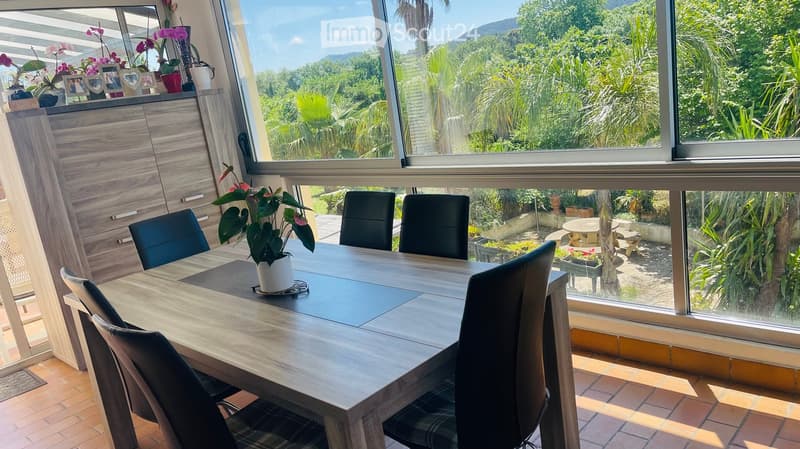 Dining table with chairs, wooden floor, large window, view of garden