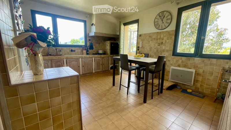 kitchen with dining area, cabinets, countertop, dining table, wall clock, windows