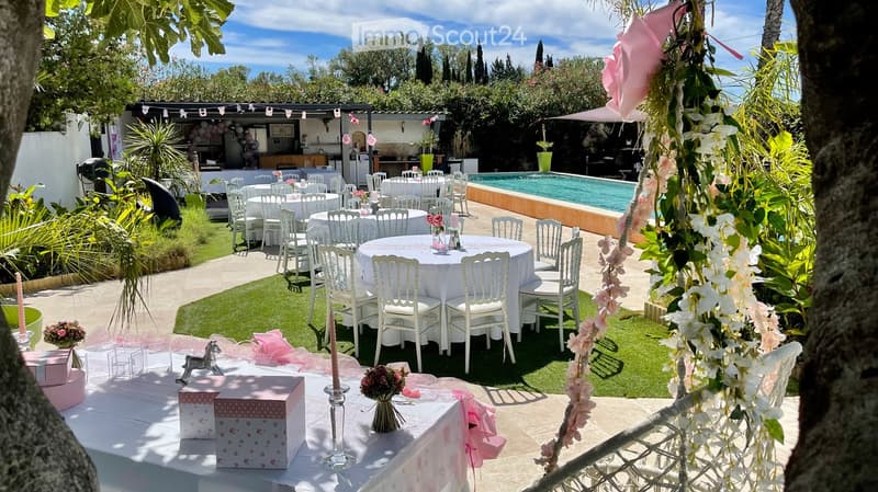 Outdoor area with tables, chairs, and decorative items for an event, swimming pool, plants, and trees