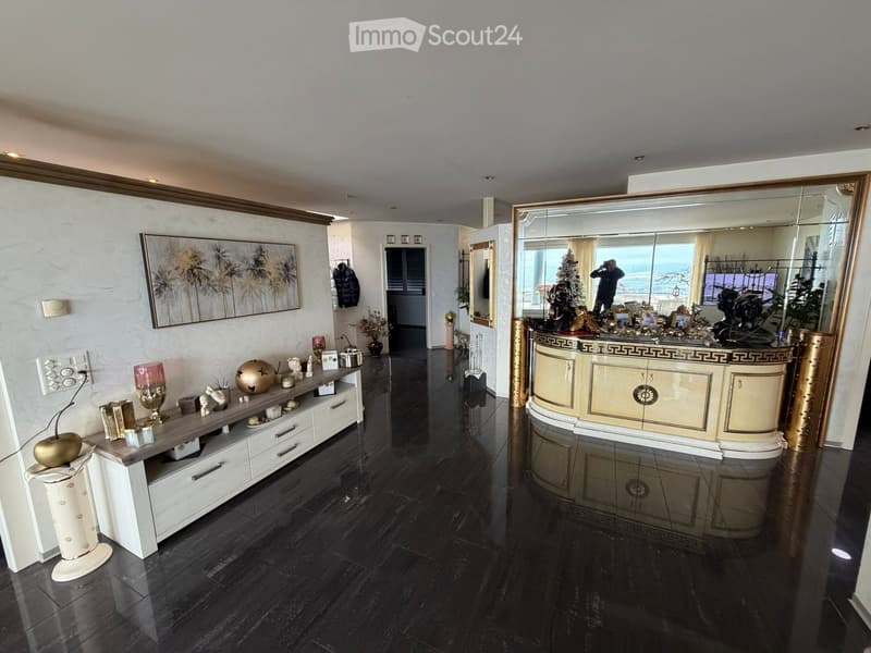 Large open space, polished wood floor, large window with city view, decorative items, and a counter