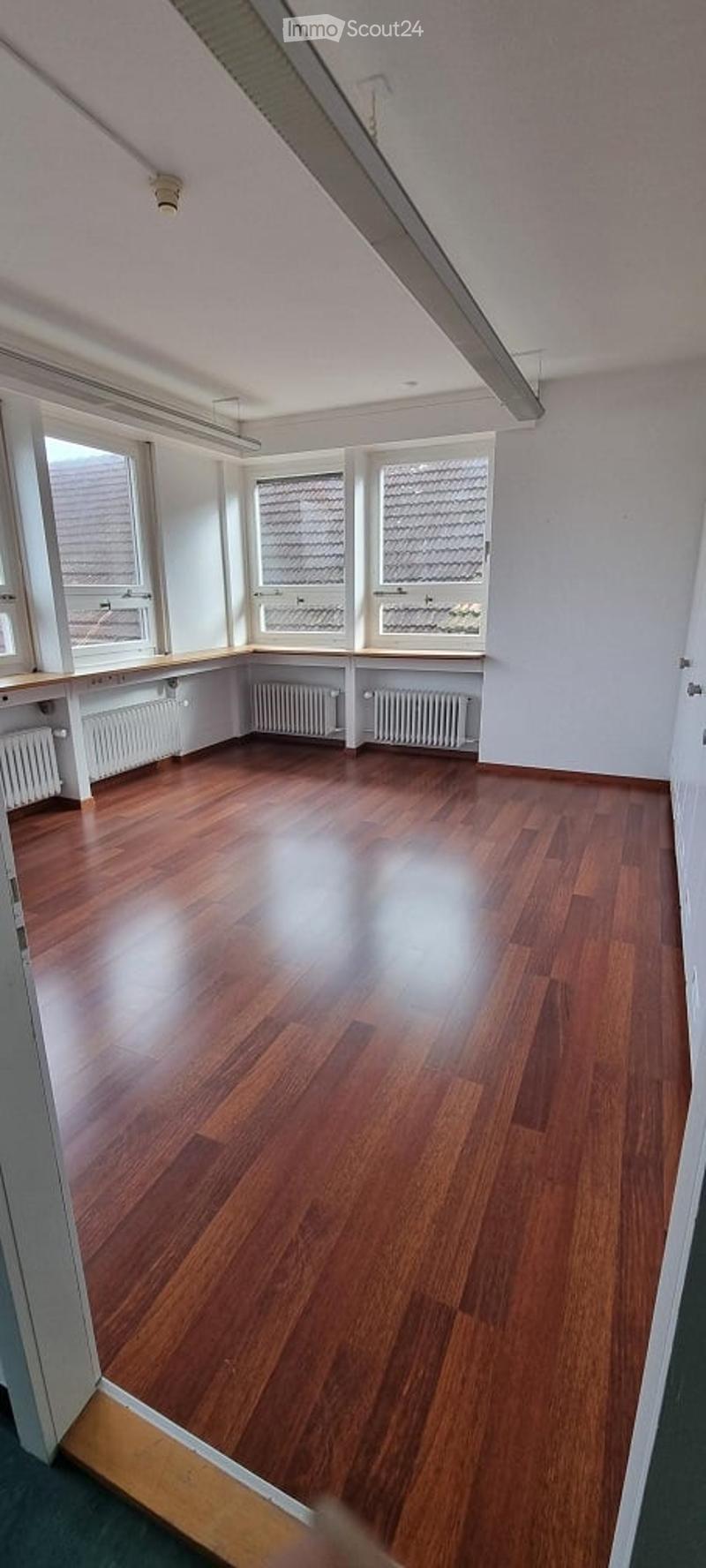 empty room with wooden floor, large windows, white walls, radiators