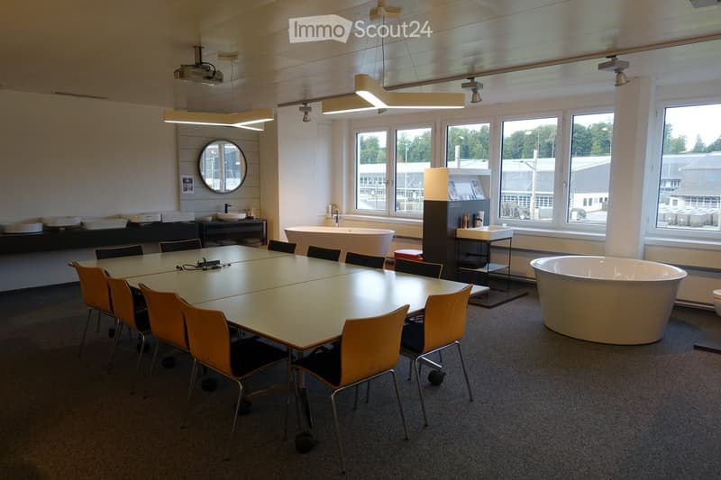 Long conference table, yellow chairs, white bathtubs, large windows, ceiling lights, projector