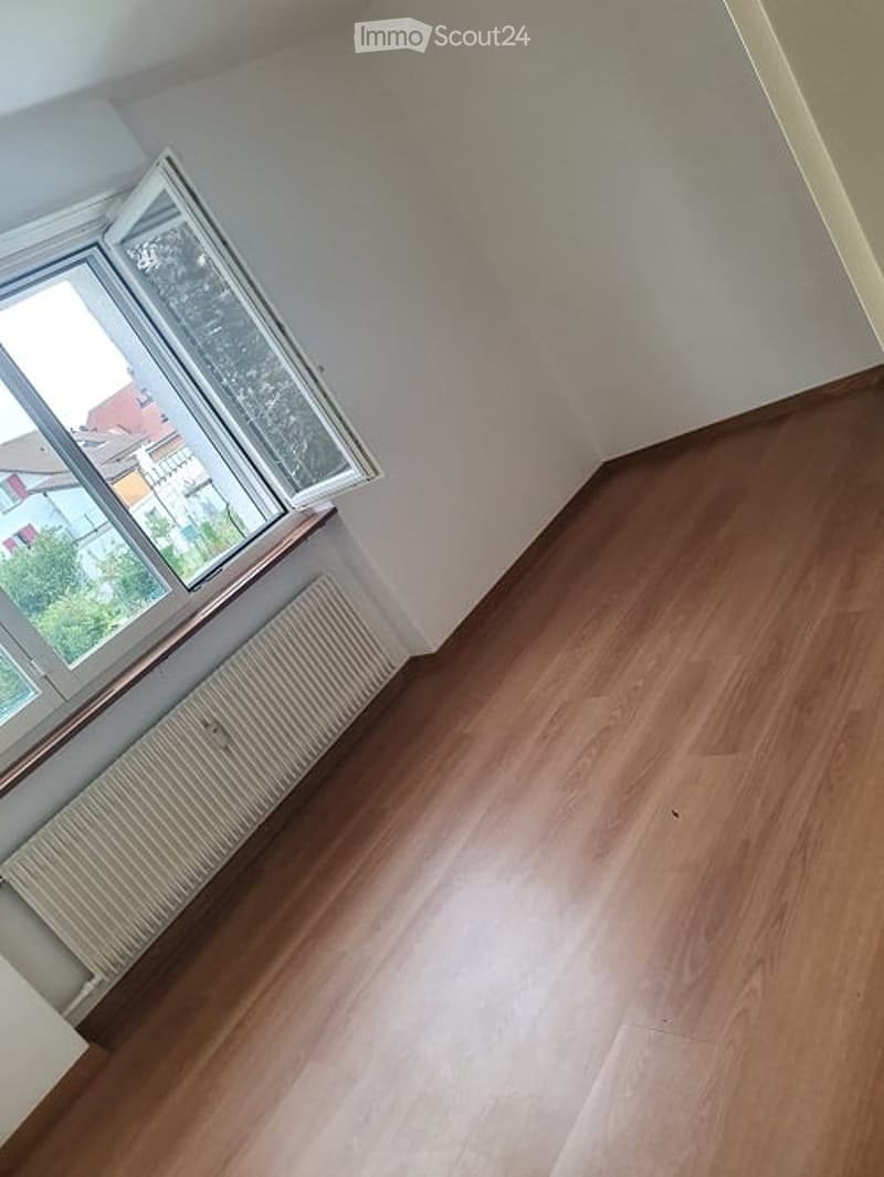 corner room with window, white radiator, wooden floor, view to outside