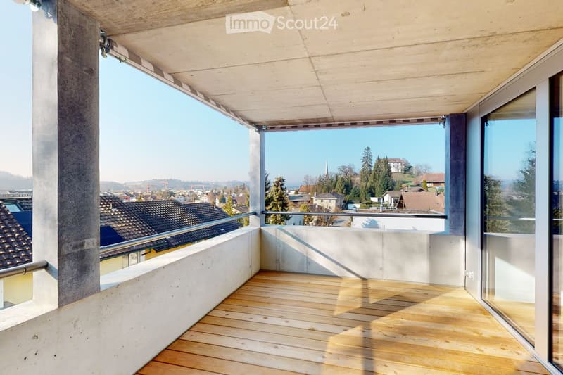Empty balcony, wooden floor, metal railings, glass doors, city view