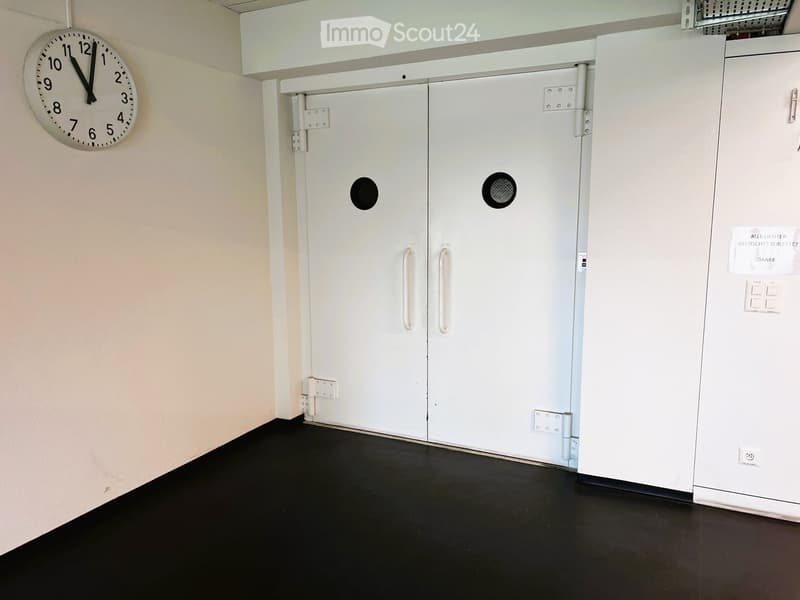 White doors with round windows, clock on the wall, empty room