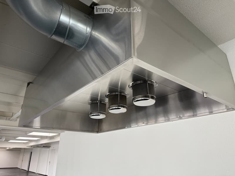 Empty room with white walls, grey floor, and modern ceiling lighting fixtures.