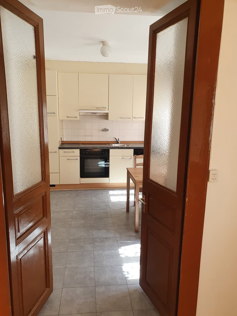 Empty kitchen with wooden counter, tiled floor, white cabinets, oven, sink, and faucet