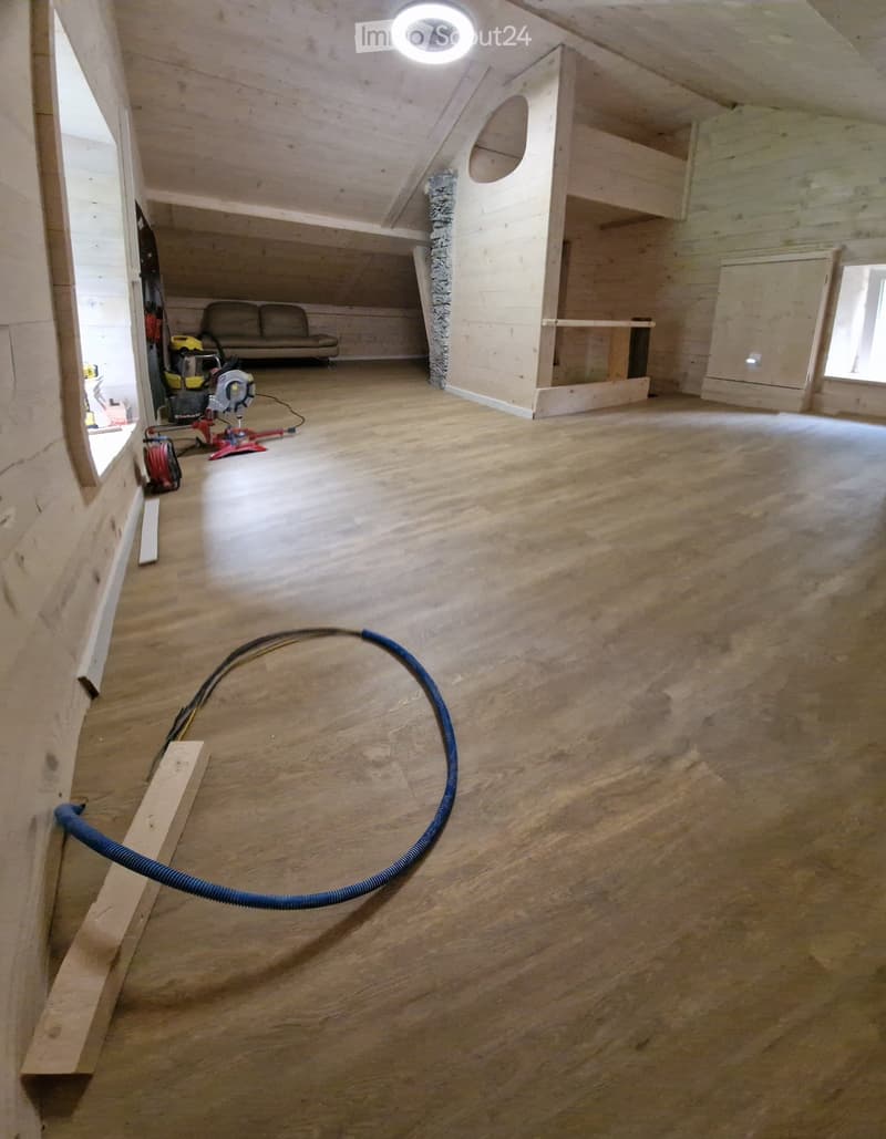 Empty room with wood floor, ceiling with a lamp, wooden sofa and objects on the floor.