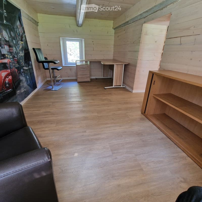 leather sofa, wooden floor, large wall art, wooden desk with drawer, window, wooden shelf, black swivel chairs