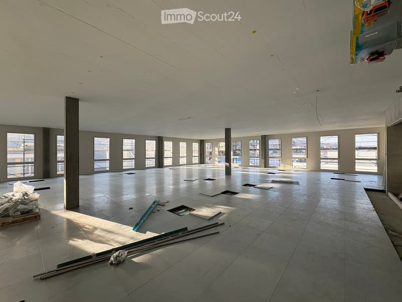 Empty room, multiple windows, high ceiling, construction materials scattered on the floor