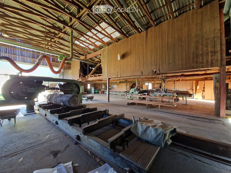 spacious factory with large windows, metal beams, concrete floors, large machinery, wooden walls