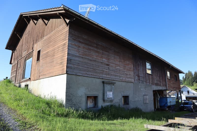 raised ground floor, wooden exterior, large windows, attached garage