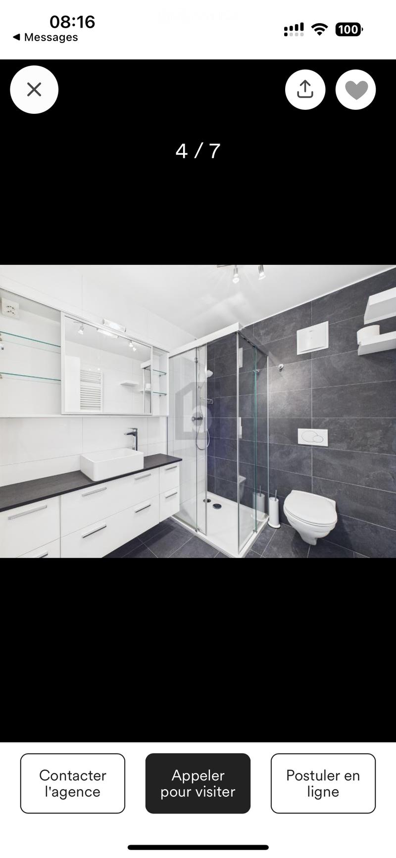 Modern bathroom with white tiles, a shower, a toilet, a vanity with a sink, cabinets, and a mirror.