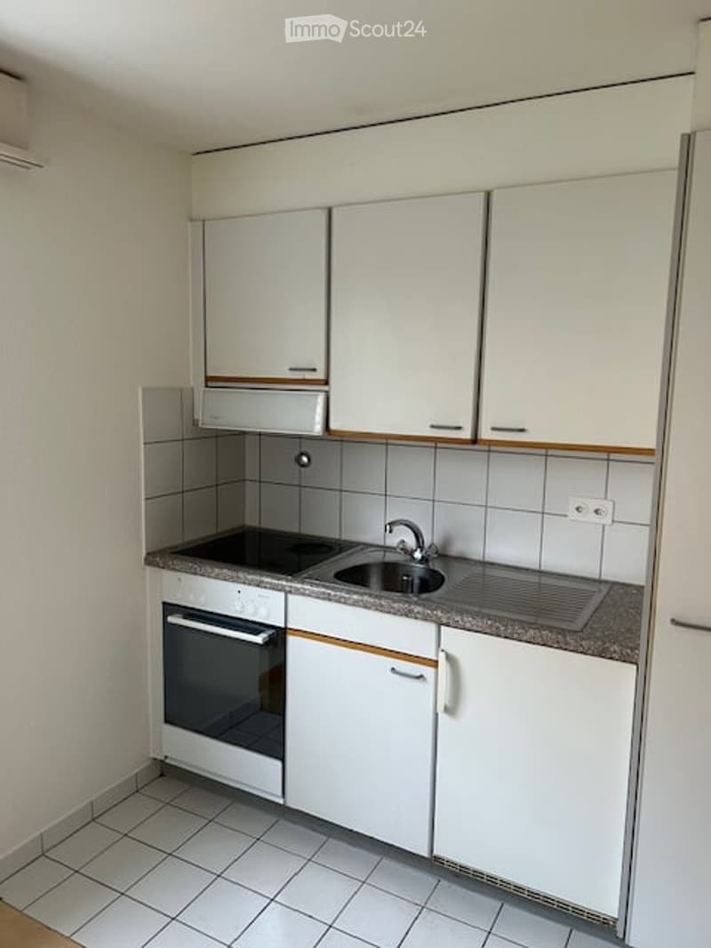 Modern kitchen with white cabinets, tiled walls, and a built-in oven. Features a sink with a faucet and a countertop.