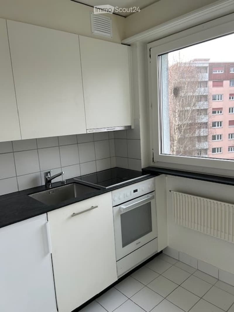 white cabinetry, black countertop, gas stove, oven, sink, faucet, radiator