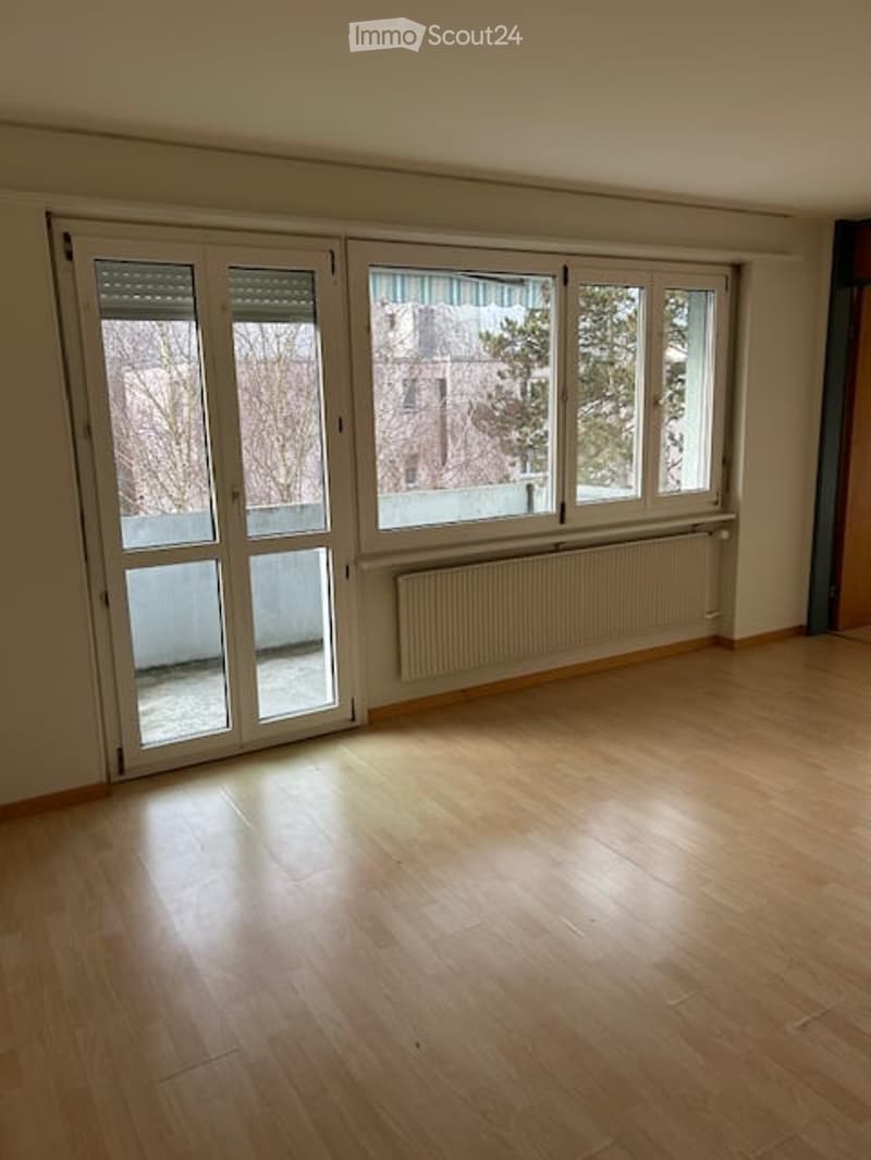 empty room with wooden floors, sliding glass doors, white walls, radiator, balcony view