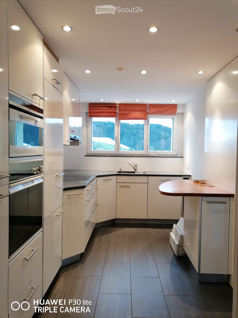 modern kitchen with white cabinets, wooden countertop, gas stove, oven, sink, dishwasher, window with view