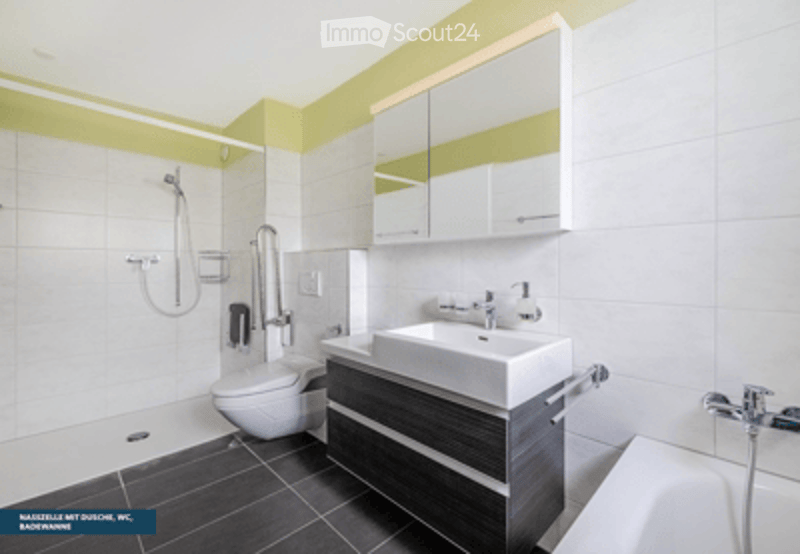 Modern bathroom with white tiles, dark grey floor, a large sink with a mirror above, a toilet, and a shower area.