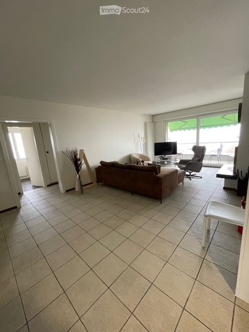 furnished living room with couch, TV, armchair, chair, glass door to balcony