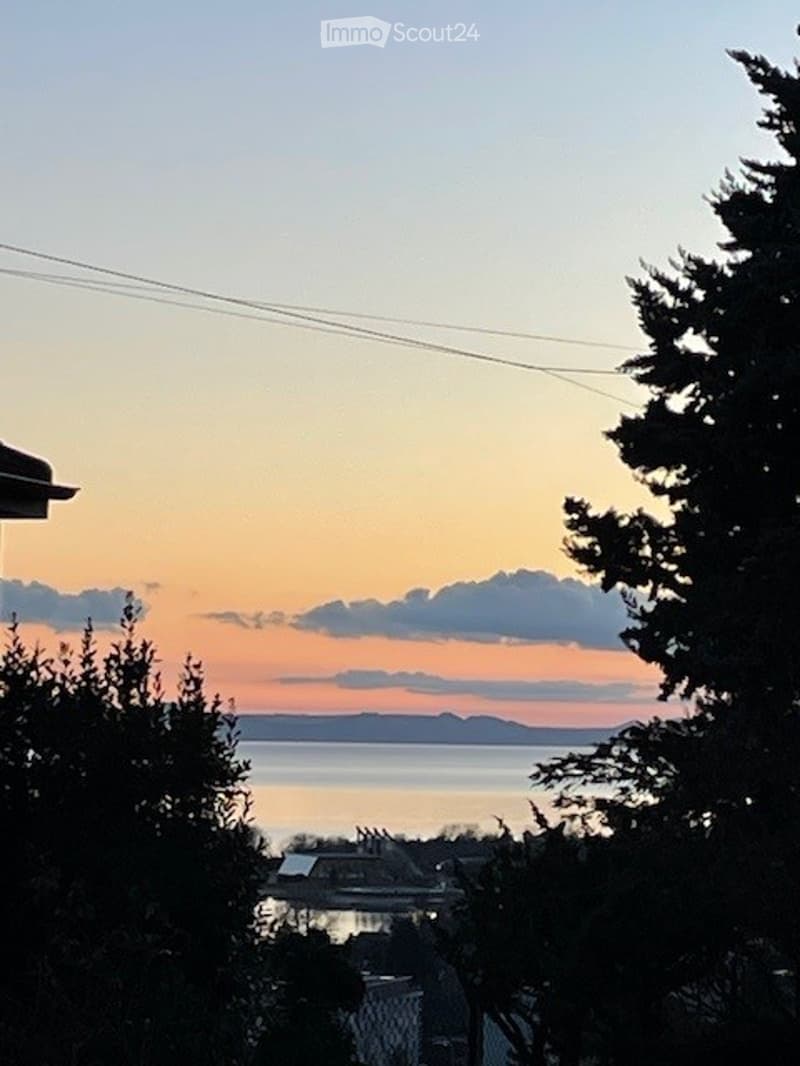 view from balcony or terrace, sea, orange sky, clouds, trees, buildings