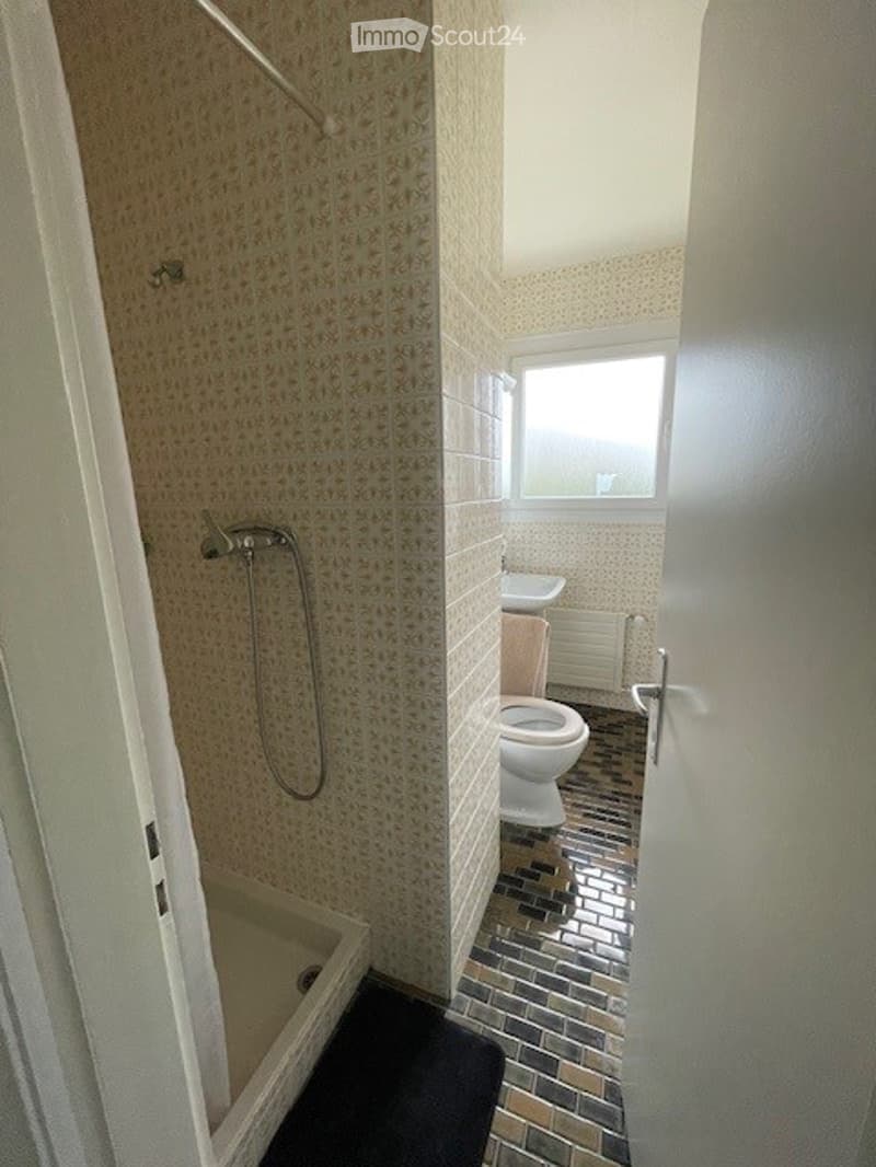 white shower, white sink, white toilet, tiled floor, window
