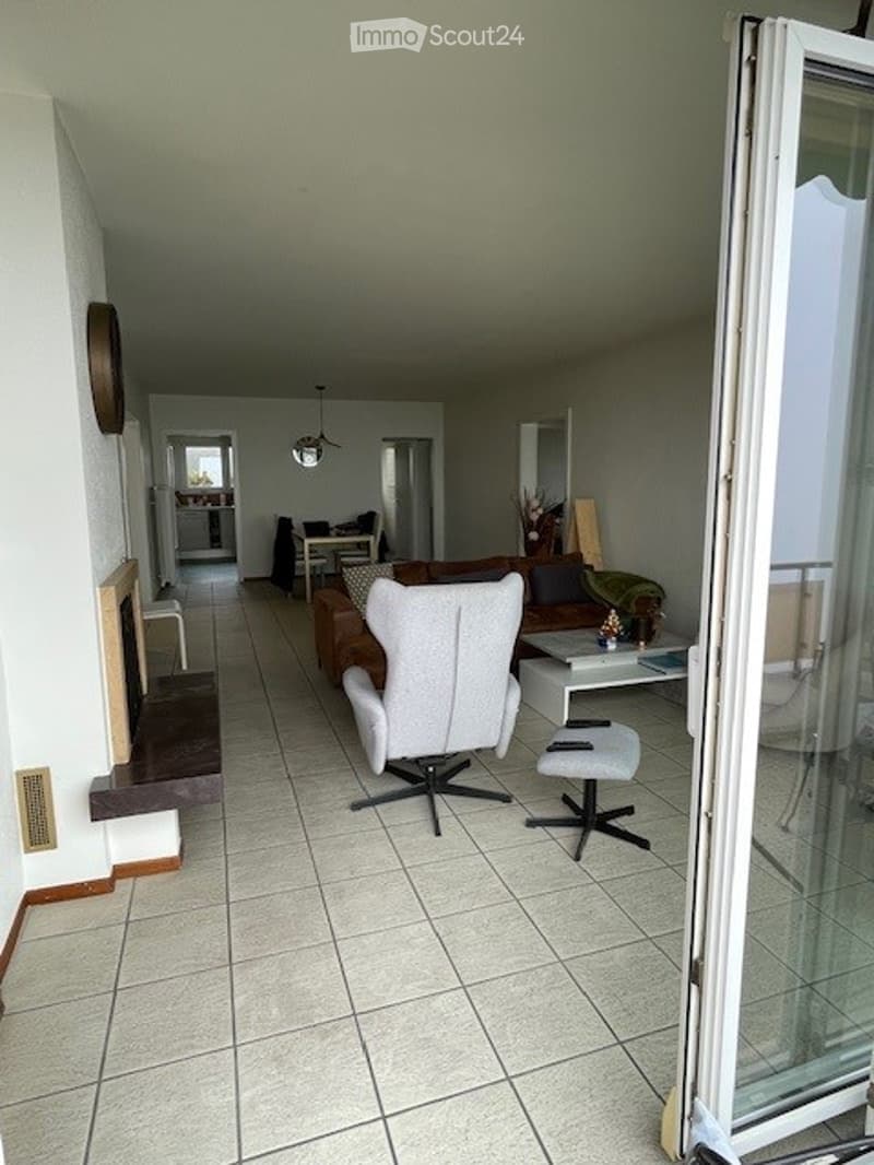 modern styled, bright room, white tiled floor, glass door leading to balcony, beige couch, white chair, black table