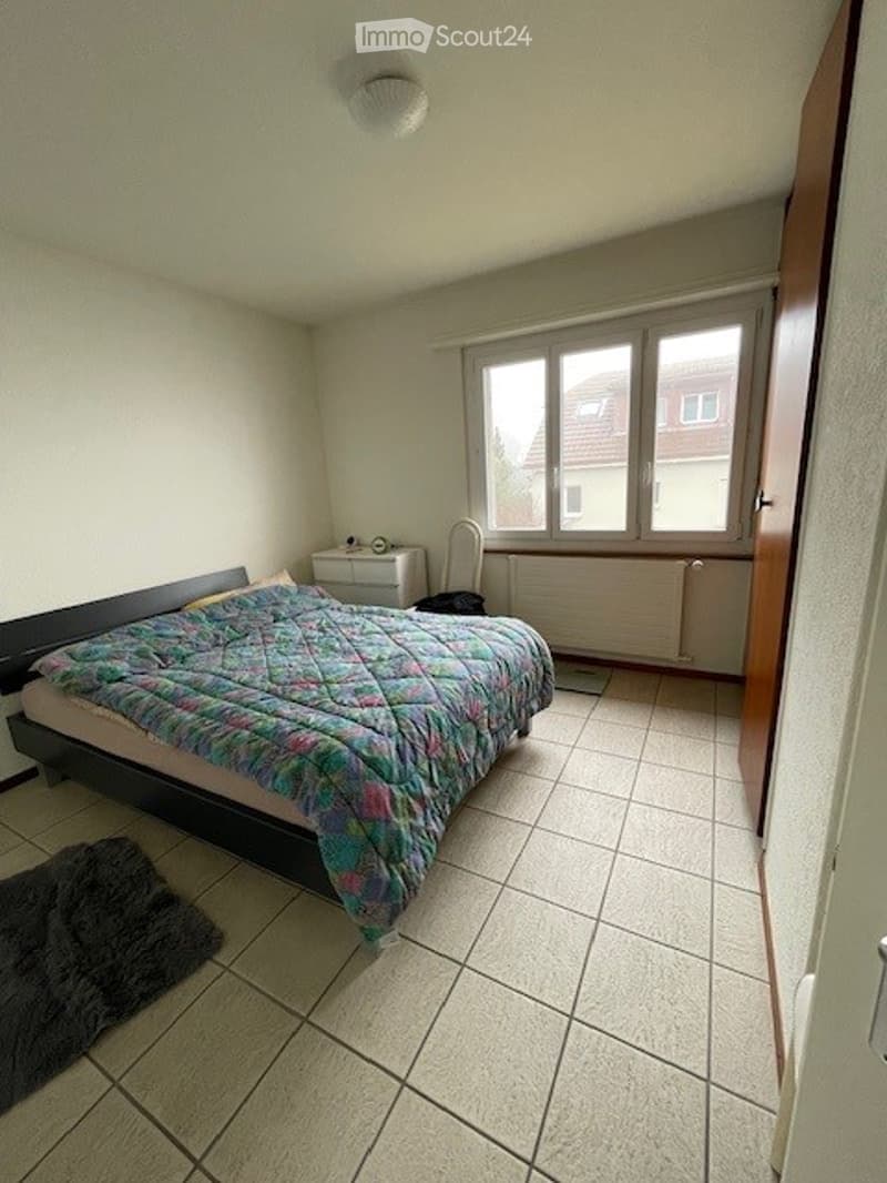 Single bed, nightstand, radiator, window, rug, chair