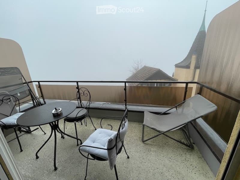 Balcony with four chairs, a table, and a chaise lounge.