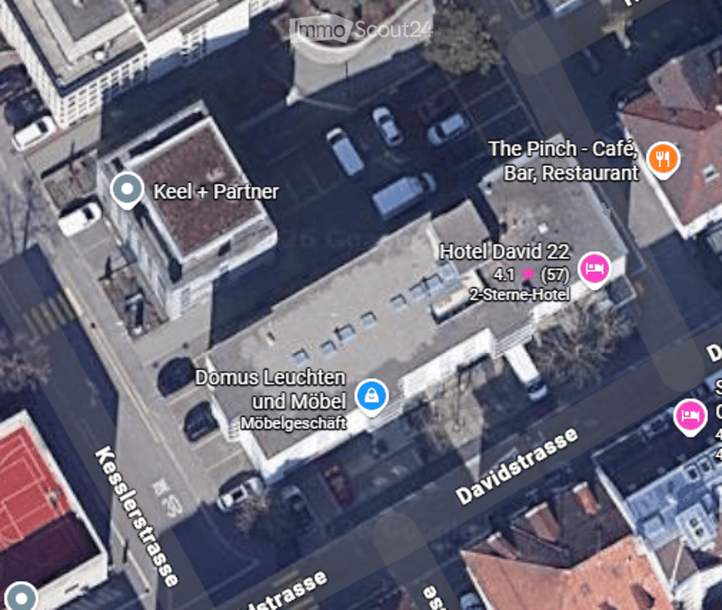 Aerial view of a city street with multiple buildings, a hotel, a restaurant, and parked cars