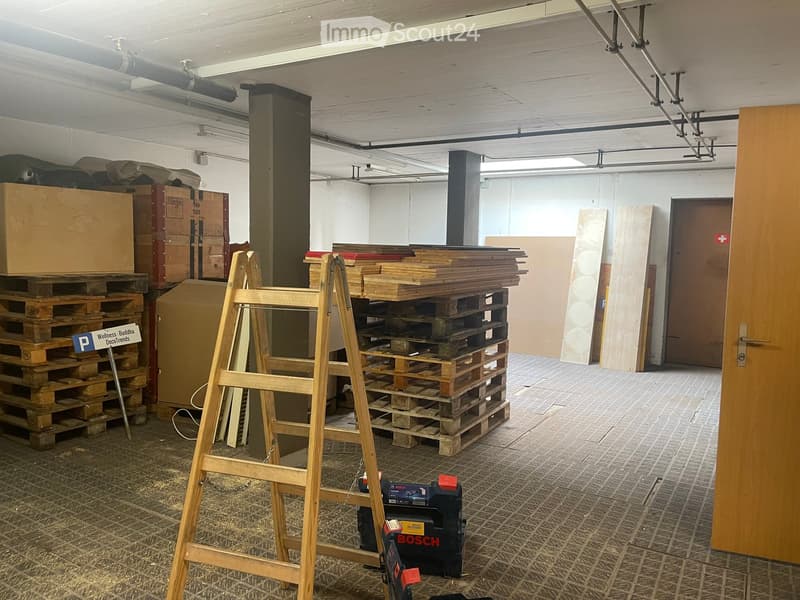 Empty room with wooden pallets, stacked cardboard boxes, a ladder, and a Bosch tool box on the floor.
