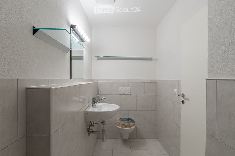 small bathroom with sink, toilet, mirror, and tiled flooring
