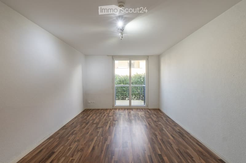 Empty room with wooden floor, white walls, sliding glass door leading to a balcony, and ceiling lights