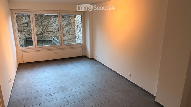 Empty room with tile flooring, large window with view outside, white walls