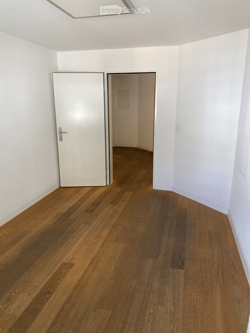 Empty room, hardwood floor, white walls, open door