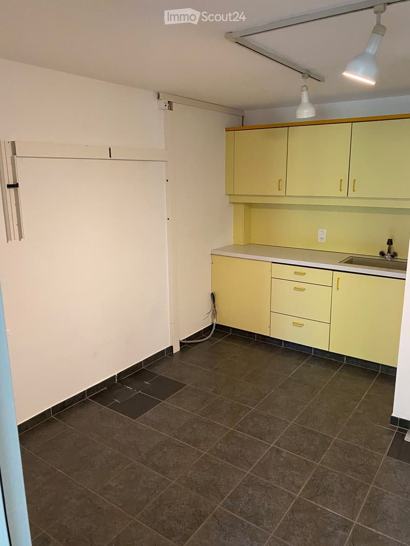 Empty laundry room with yellow cabinets, tiled floor, light fixtures, power outlet, sink, and faucet.