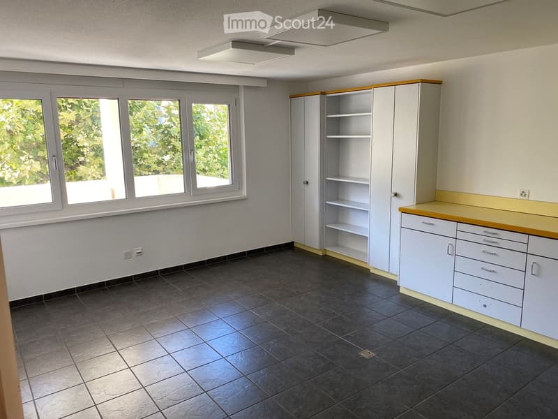 Empty room with black tiled floor, white cabinets, windows, shelves, and yellow countertops