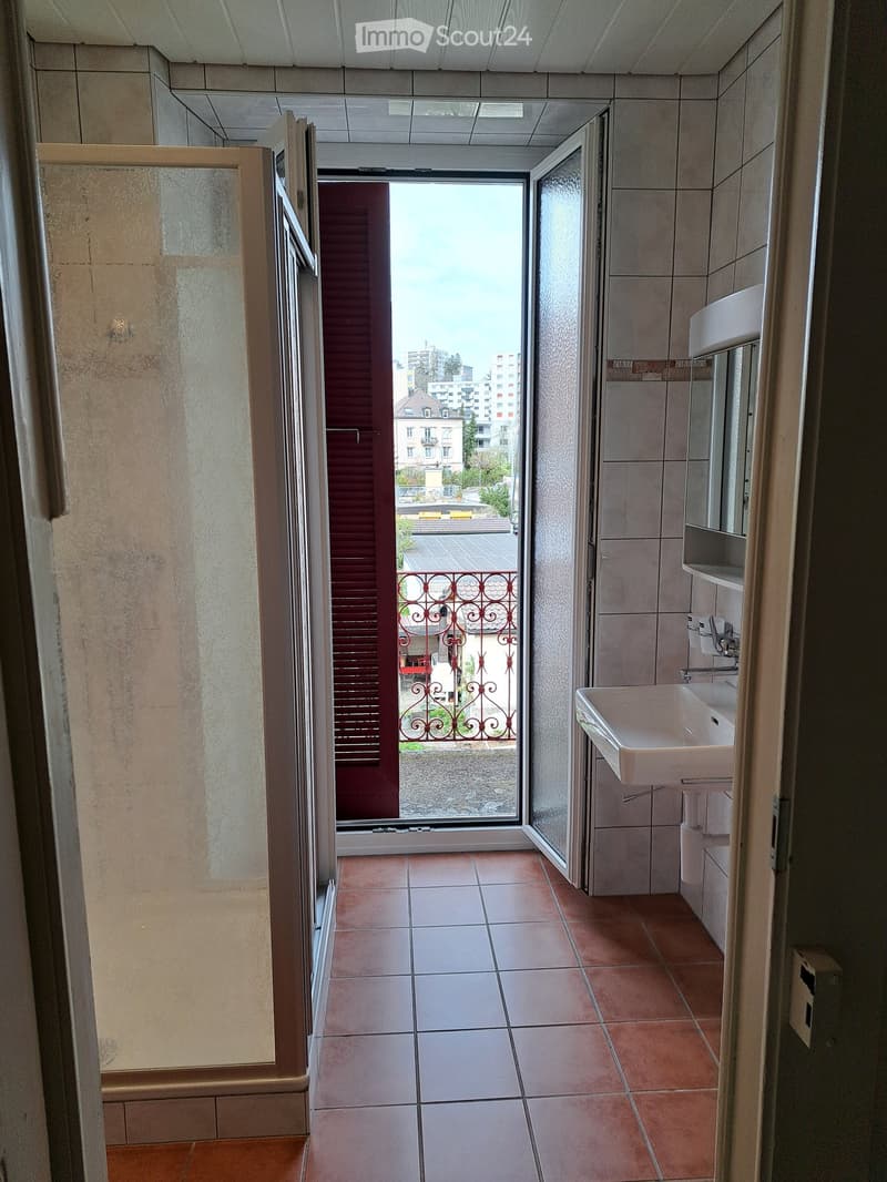 shower stall, sink, tiled floor, mirror, red balcony outside