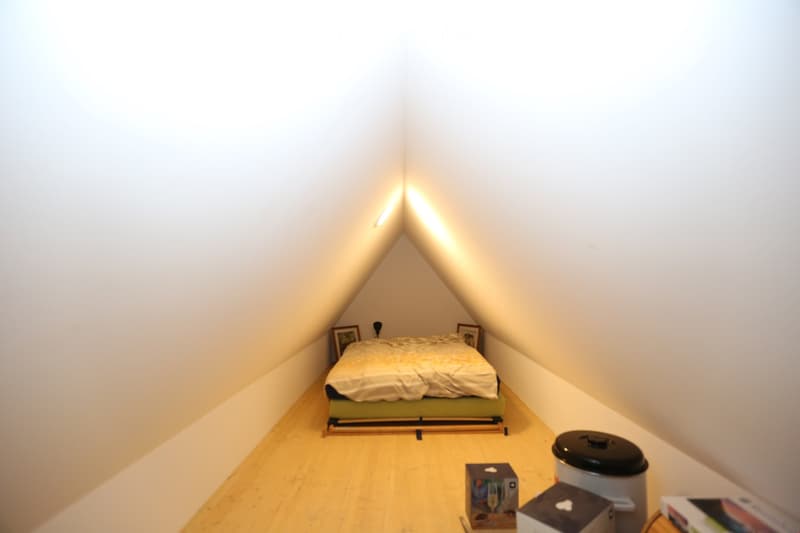 Atria bedroom with a bed, a window, a tripod, a table with books and picture frames, and a kettle